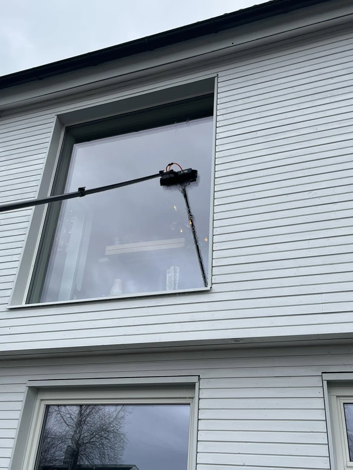 Stang med børste mot stort vindu på hvit trevilla, fra et av oppdragene våre